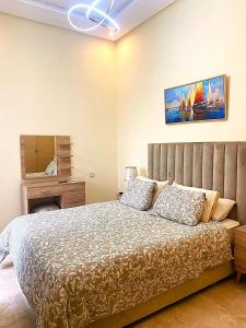 a bedroom with a bed and a desk and a mirror at Superbe appartement à bouznika avec vue sur piscine et jardin privatif in Bouznika +20 photos