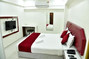 a bedroom with a large bed with a red and white blanket at Hotel Chava Executive in Pune