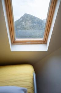a window above a bed in a room with a mountain at Precioso ático con vistas l WIFI l P l trastero in Sallent de Gállego