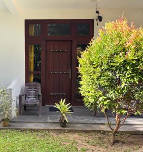 Una puerta de madera con una silla en un porche. en Jimi Villa 99, en Bentota