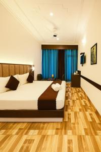 a bedroom with a large bed with blue curtains at Kasauli View Resort # Parking # lift # Garden # Restaurant # Open Terrace # On Road Location in Kasauli