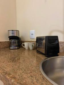 a counter with a toaster and a coffee maker on it at Studio TOP pra homeoffice, internet voando in Macaé