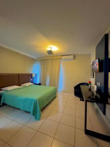 a bedroom with a green bed and a flat screen tv at Studio TOP pra homeoffice, internet voando in Macaé
