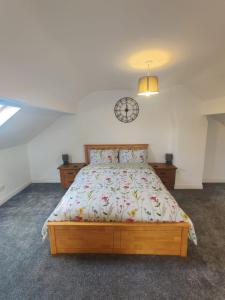 a bedroom with a bed with a clock on the wall at Chic 2-Bed Loft Bungalow, Cleveleys, Near Beach in Blackpool