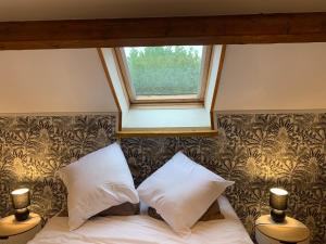 a bedroom with a bed with two pillows and a window at Maison Lilou in Garnay