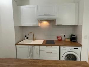 a kitchen with white cabinets and a sink and a dishwasher at Joli studio climatisé avec terrasse au calme in Nice