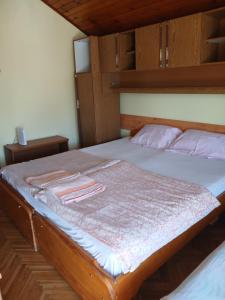 Un dormitorio con una cama con marco de madera. en HOSTEL BATA APARTMANI, en Kanjiža 5 fotos más