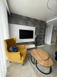 a living room with a yellow chair and a table at Apartament Holiday Crystal in Rewal +19 photos
