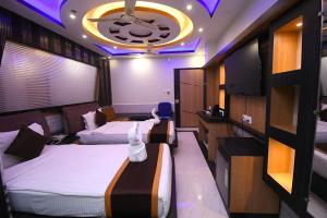 FatikrāiにあるHotel Adhunikのベッド2台とテレビがあるホテルの部屋