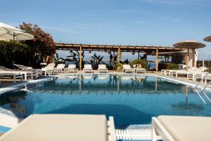 a large swimming pool with white chairs and umbrellas at Erosea Beach Resort in Kavos