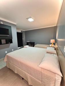 a bedroom with two beds and a flat screen tv at Hotel Boa Viagem in Barra do Garças