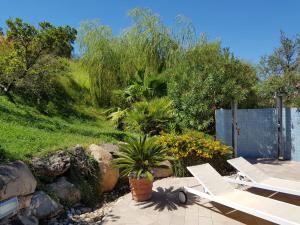 a patio with two white chairs and a garden at Villa Starlight vista mare La Caletta in Santa Lucia