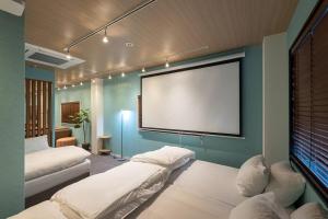 a room with two beds and a projection screen at TasoneUrbanStayOsaka 梅田北EFB2F in Wada