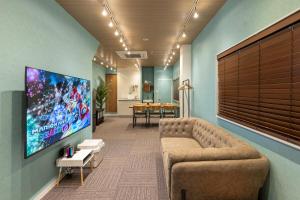 a lobby with a couch and a flat screen tv at TasoneUrbanStayOsaka 梅田北EFB2F in Wada