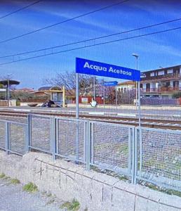 a fence with a blue sign next to a train station at Andrew House in Ciampino
