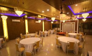 a banquet hall with white tables and chairs and a screen at Hotel Adhunik in Fatikrāi