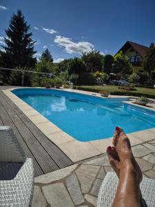 a person laying on a chair next to a swimming pool at Ihre Auszeit am Golfplatz in Meisdorf