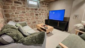 a living room with a couch and a flat screen tv at La Cav'O Bulles - Balnéo privative - parking in Obernai