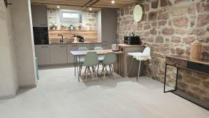 a kitchen with a table and chairs and a stone wall at La Cav'O Bulles - Balnéo privative - parking in Obernai