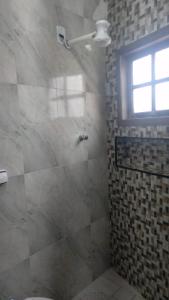 a bathroom with a shower with a window and a toilet at Kitnet acolhedora para 2 pessoas in Ribeirão Pires