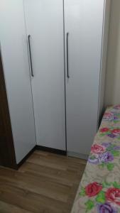 three white cabinets in a room with a bed at Kitnet acolhedora para 2 pessoas in Ribeirão Pires