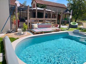 a large swimming pool in a yard with a bench at Jadis sous la gloriette in Sancoins