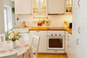 a kitchen with white cabinets and a table with a vase of flowers at Gîte du Moulin de Maître Pierre in Payrignac