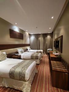 a hotel room with three beds and a television at فندق مواسم سمرقند اجياد توصيل مجانى للحرم in Al Masfalah