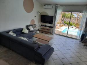 a living room with a couch and a tv at Ylang Ylang in Saint-Leu