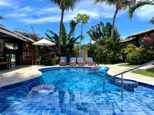 a pool at a resort with chairs and palm trees at Pousada Tartaruga Boutique Hotel in Pipa