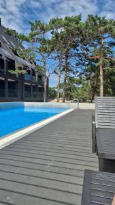 a swimming pool with a bench next to a building at Czarna Perła 109 luksusowy apartament,basen,garaż,taras Hel in Hel