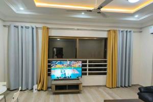 a living room with a tv and yellow curtains at 2 bedroom Apartment - East legon in Accra