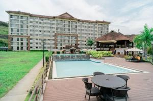 a large hotel with a pool and a table and chairs at 7F Cozy 2BR Condo - Central Location in Lapasan