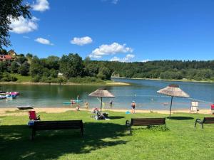 Gente en una playa con sombrillas y un cuerpo de agua. en Domki Cypel Zawóz, en Zawóz