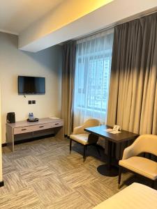 una camera d'albergo con tavolo, sedie e TV di Onora Hotel a Ulaanbaatar