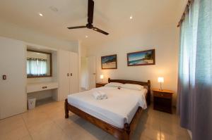 a bedroom with a bed and a ceiling fan at Villas Idea in Anse Kerlan