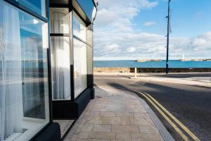 a building on the side of a street next to the ocean at One Shore Street in Donaghadee