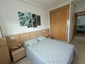 a bedroom with a bed and a wooden cabinet at ACV - Torremar-2ª linea planta 8 norte in El Borseral