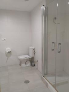 Un baño blanco con inodoro y ducha. en Camping El Burgo, en Orellana la Vieja