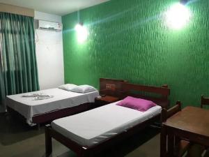 a room with two beds and a green wall at Transito Hotel in Araguaína