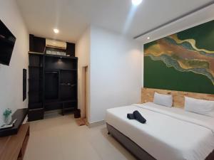 a bedroom with a bed and a painting on the wall at D'Hills Hotel in Bukittinggi