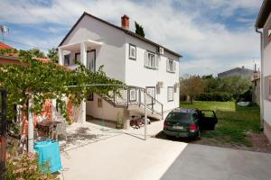 a white house with a car parked in the driveway at Apartments MTV - private parking, Fast Wi-Fi & Steps to the Beach in Zadar