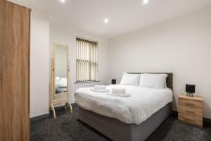 ein Schlafzimmer mit einem großen weißen Bett und einem Spiegel in der Unterkunft Modern & Stylish 1 Bed Budget Apartment in Central Halifax in Halifax