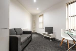ein Wohnzimmer mit einer Couch, einem Fernseher und einem Tisch in der Unterkunft Modern & Stylish 1 Bed Budget Apartment in Central Halifax in Halifax