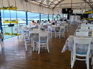 un restaurante con mesas y sillas blancas y gente comiendo en Lotos Hotel, en Balchik 48 fotos más