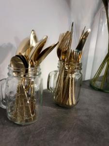 two glass jars filled with forks and knives on a table at GLAMOUR Style Apartment in Cluj-Napoca +27 photos