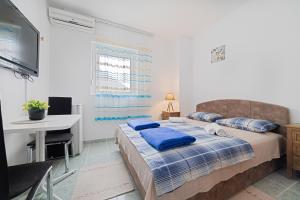a bedroom with a bed with blue pillows and a desk at Apartment Dragicevic 3 with Garage in Budva