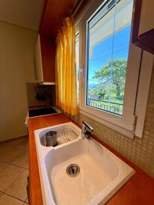 een wastafel in een keuken met een raam bij Trizonia View Beach House - Glyfada Village by MPS in Glyfada Fokidas