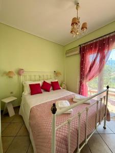 een slaapkamer met een bed met rode kussens en een raam bij Trizonia View Beach House - Glyfada Village by MPS in Glyfada Fokidas