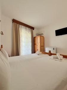 a bedroom with a large white bed and a window at Maria's Rooms in Skala Rachoniou